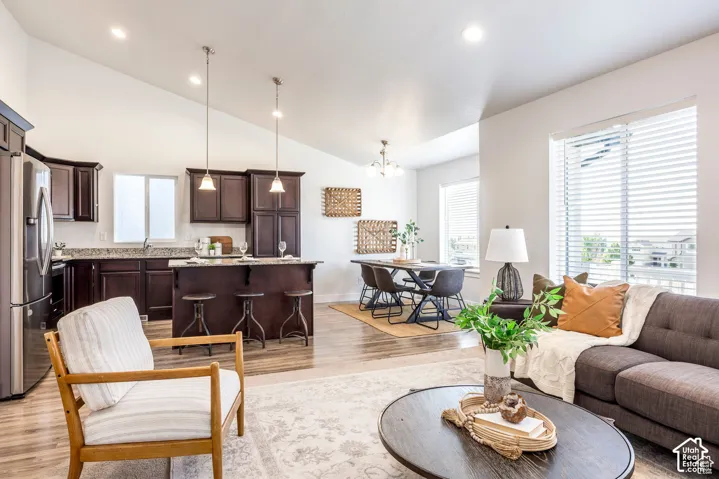 Vaulted ceilings, wood-finish flooring, dark wood cabinetry, stainless steel appliances, and large windows with blinds