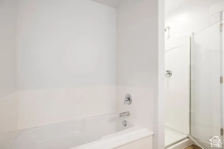 White integrated bathtub with chrome fixtures and an adjacent standing shower with a clear glass enclosure