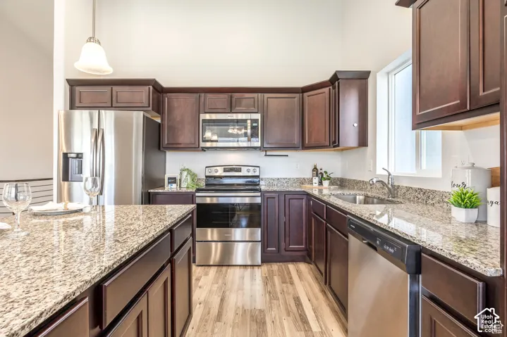Kitchen featuring wood-finish flooring, dark wood cabinetry, granite countertops, and stainless steel appliances