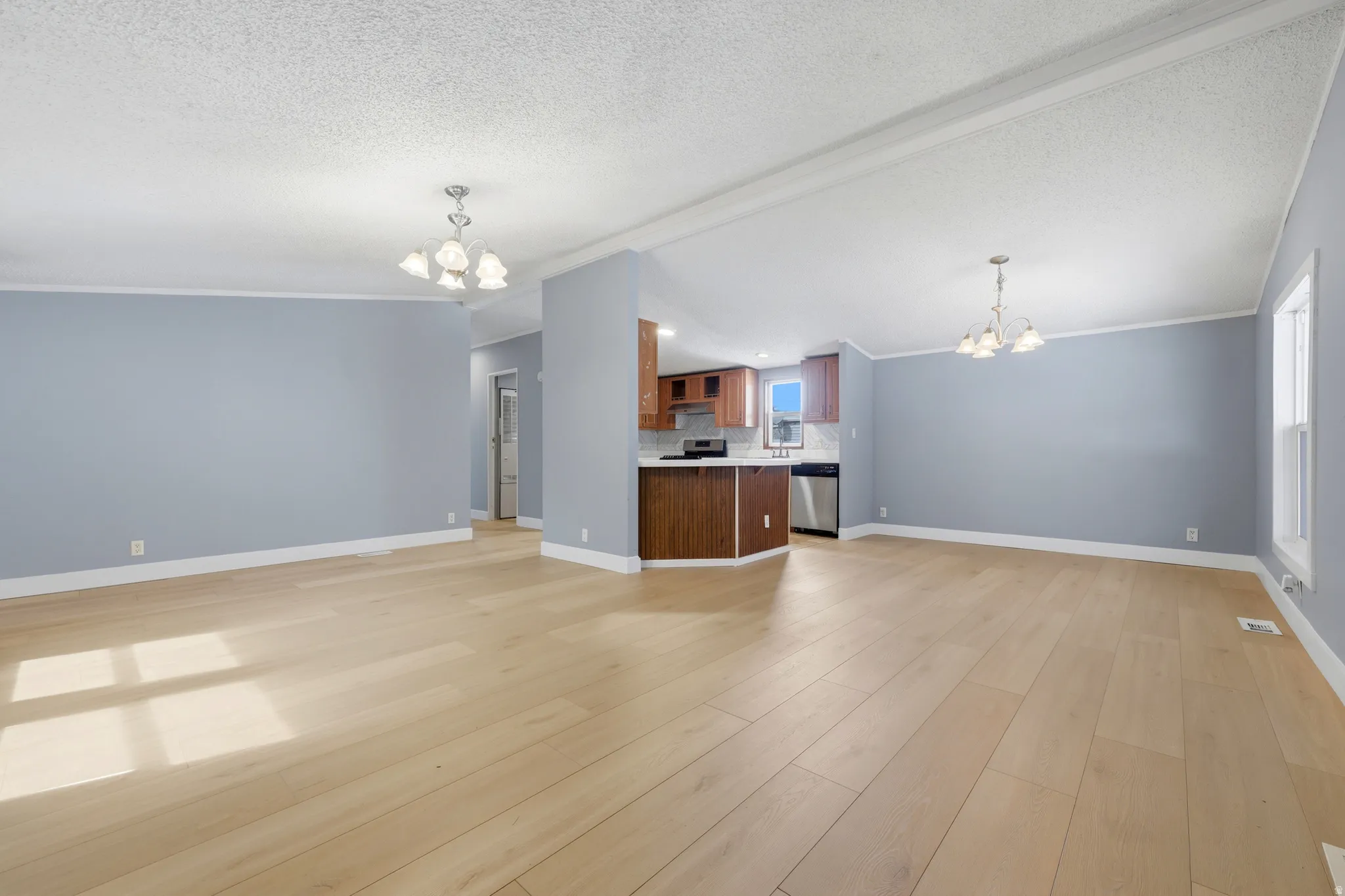 Open-concept living area featuring wood-finish flooring, recessed lighting, a kitchen with wood cabinetry, and stainless steel appliances