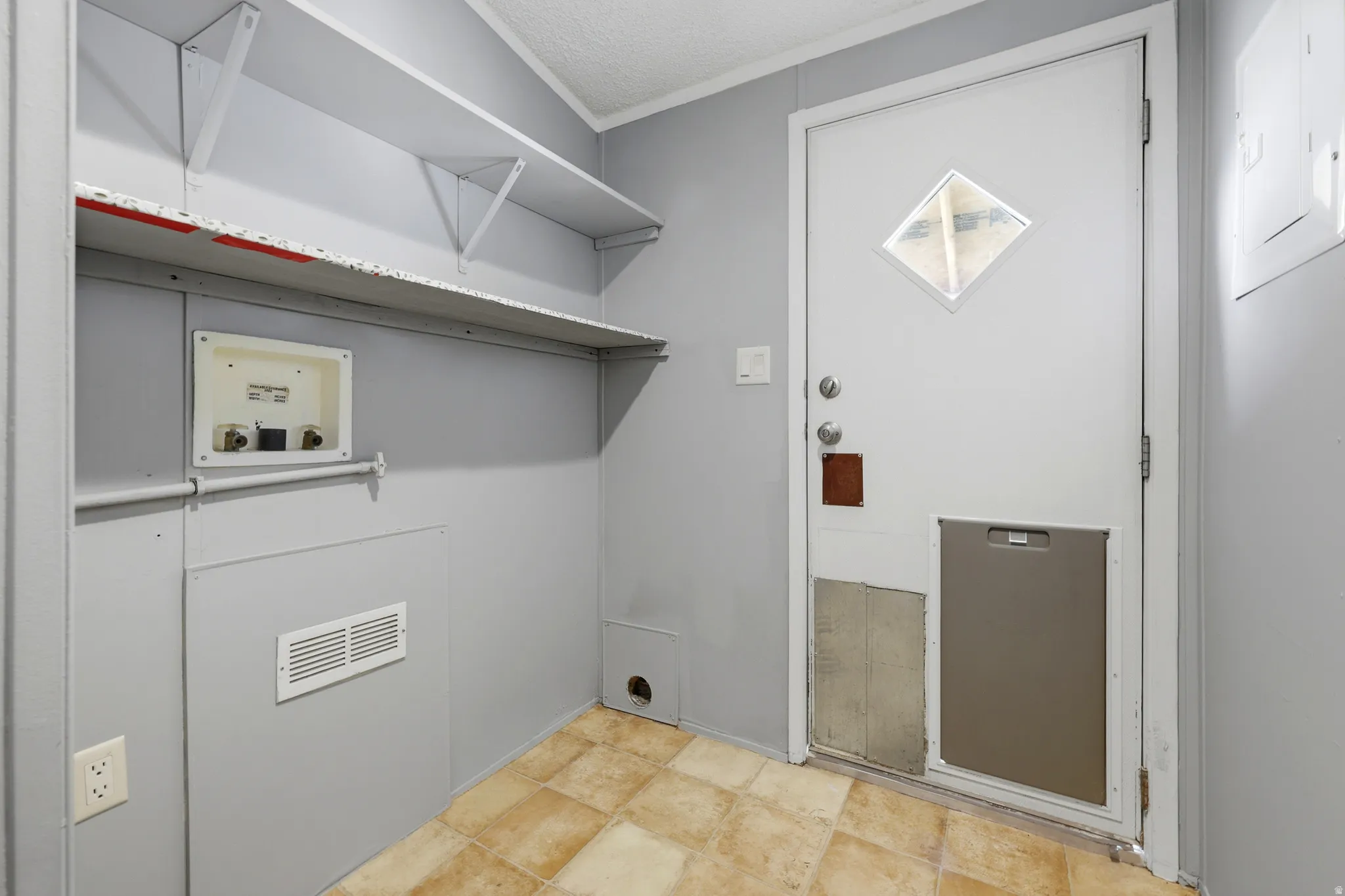 Utility area with built-in shelving, vinyl flooring, and a white exterior door with a diamond-shaped window