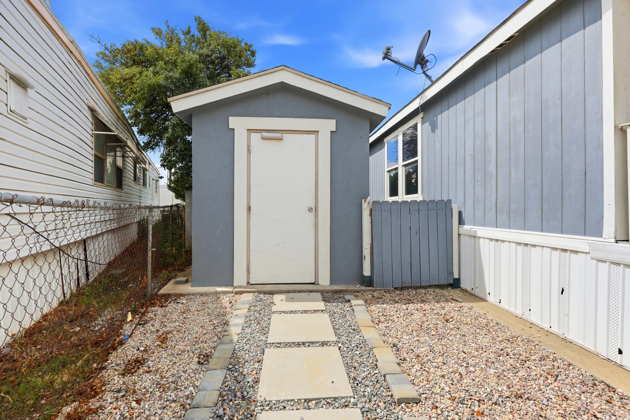 Detached storage shed with a light-colored door and trim