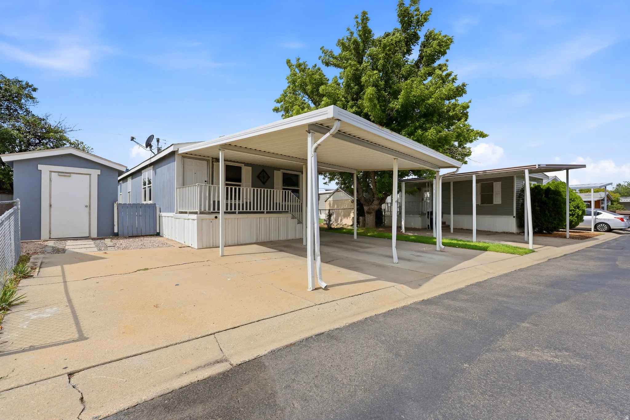 Covered carport, porch with white railing, and detached shed