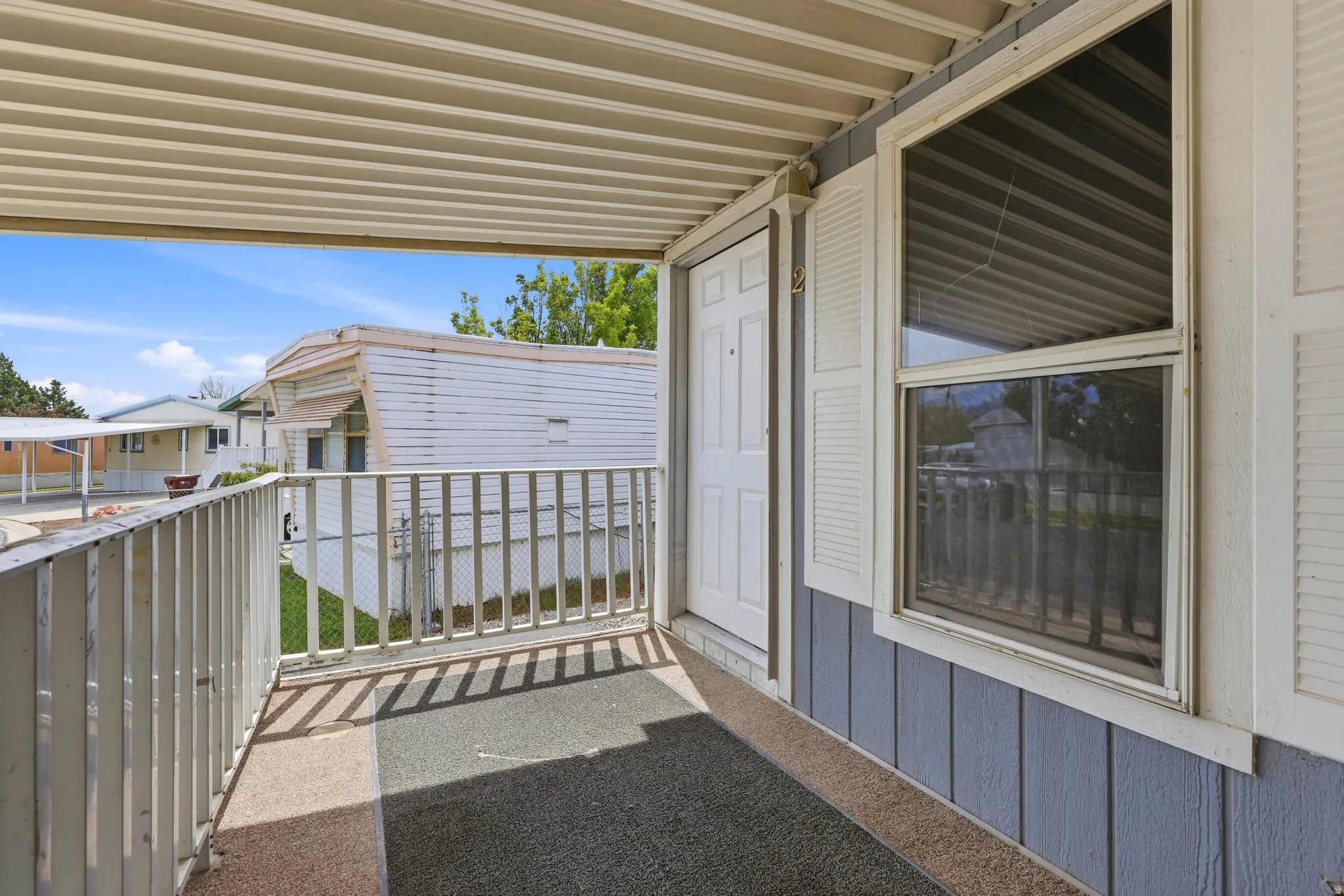 Covered porch with a white railing, siding exterior, and a paneled entry door