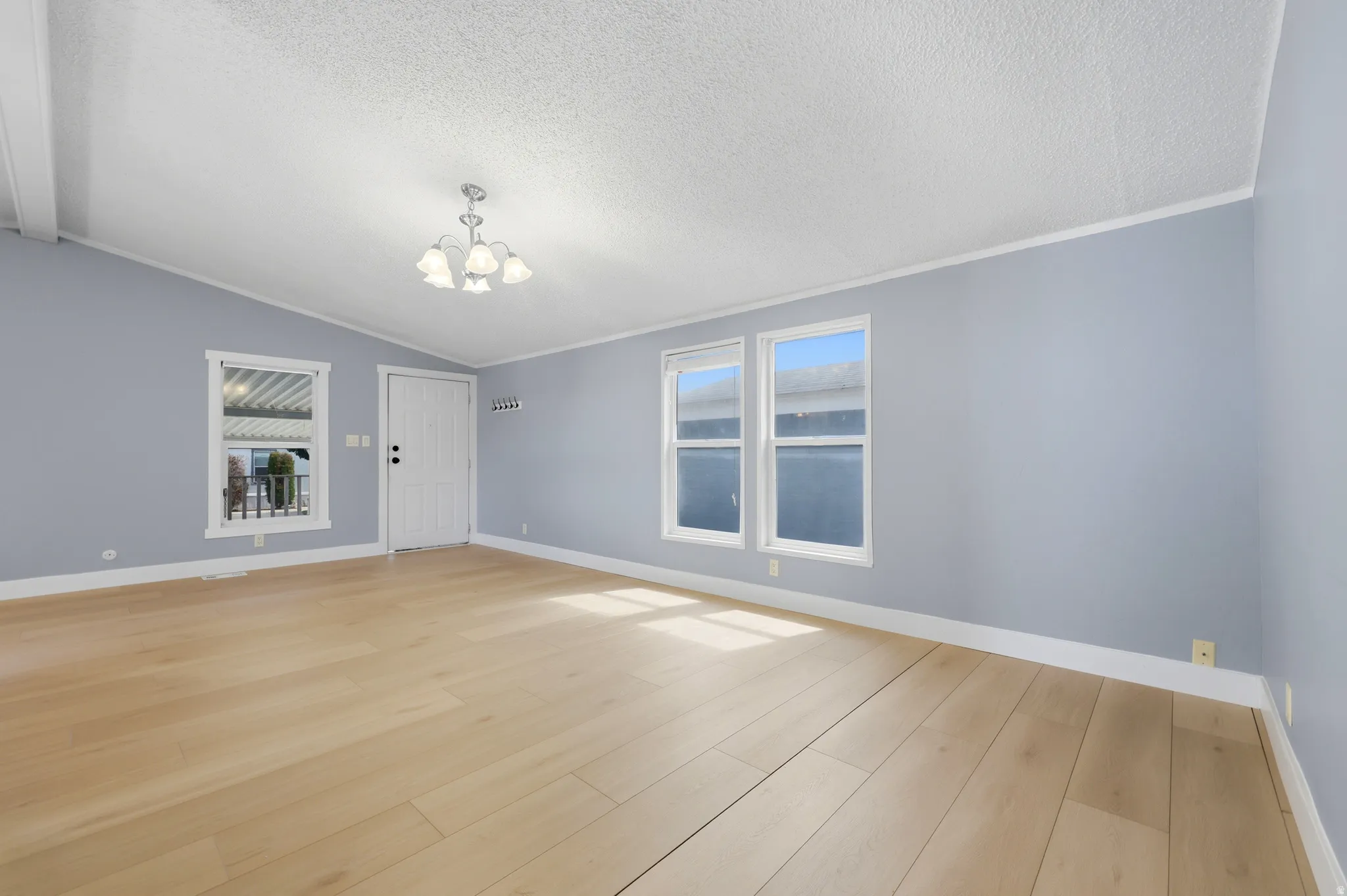 Wood-finish flooring with white trim and a vaulted ceiling