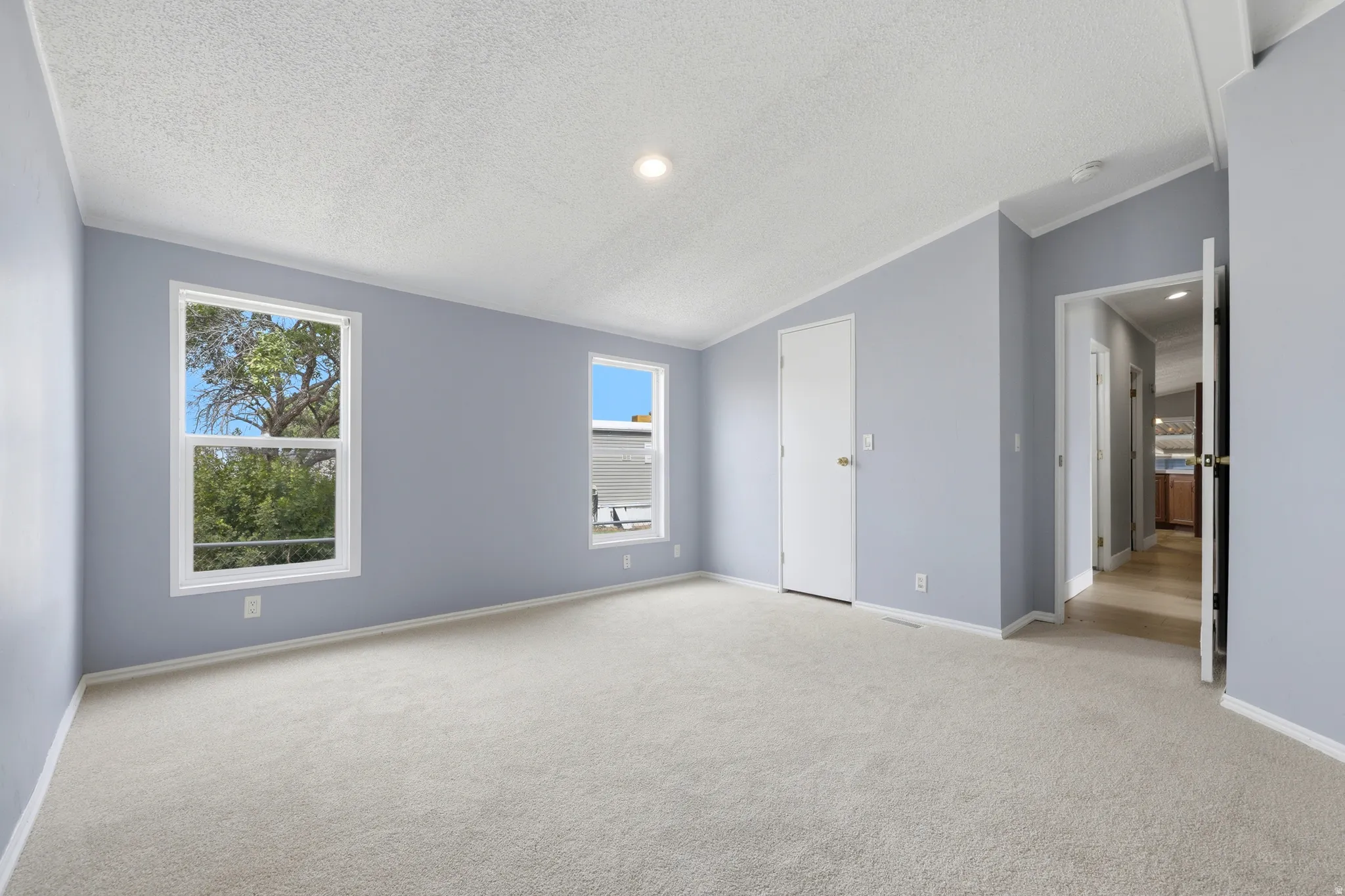 Carpeted room with light-toned walls, white trim, recessed lighting, and dual windows