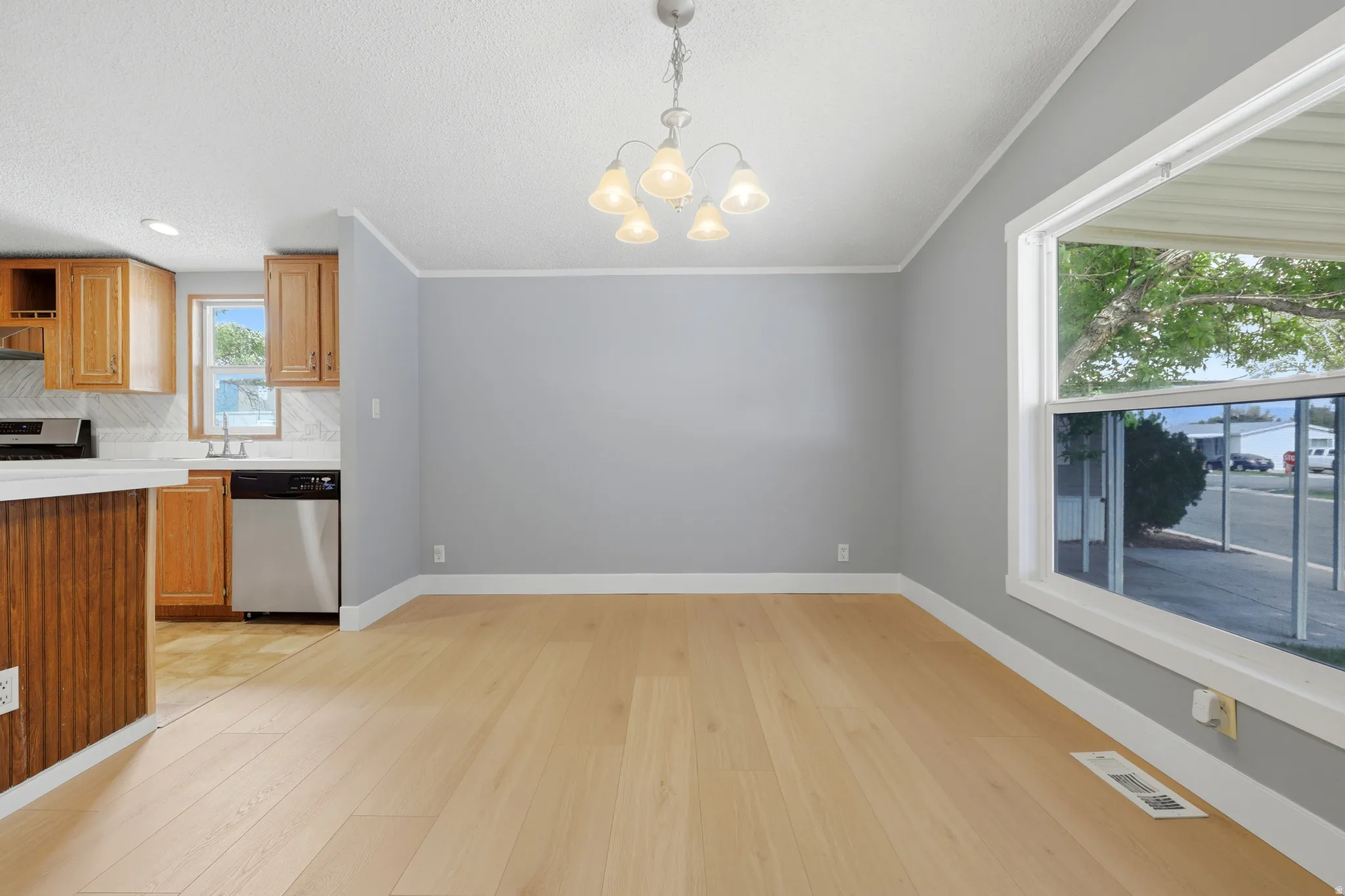 Light wood-finish flooring with a white trim, neutral wall color, and a chandelier lighting fixture