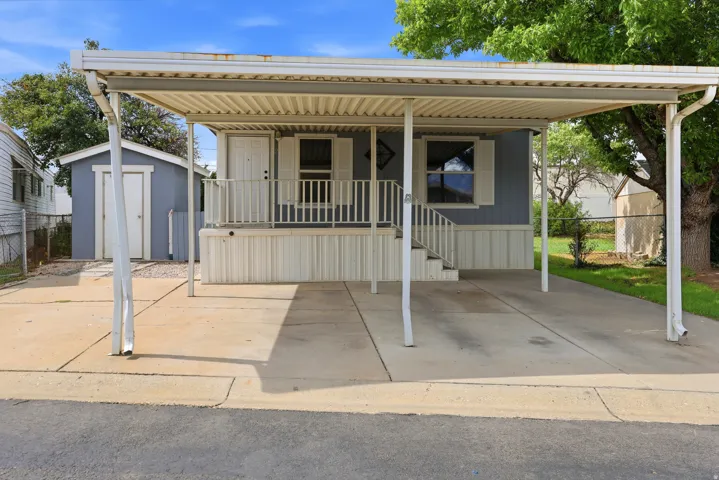 Carport with concrete driveway, light blue siding, white trim, and a covered porch with white railing