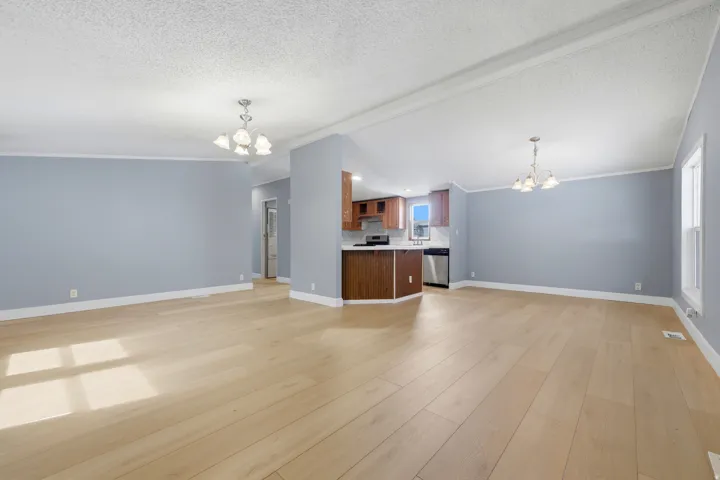 Open-concept living area featuring wood-finish flooring, recessed lighting, a kitchen with wood cabinetry, and stainless steel appliances