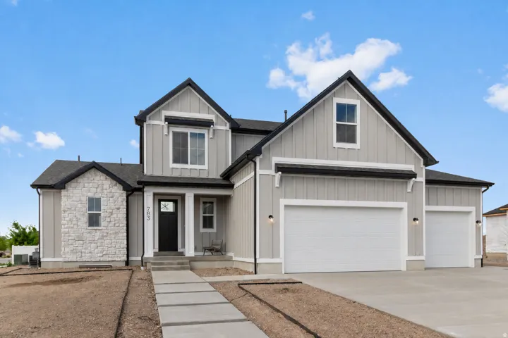 Contemporary home exterior featuring board and batten siding, stone facade accents, a dark-paneled front door, and multiple garage doors