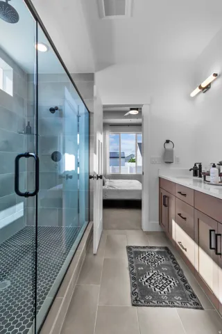 Glass-enclosed shower with a rainfall shower head and hexagonal tile flooring, framed by large-format tile walls