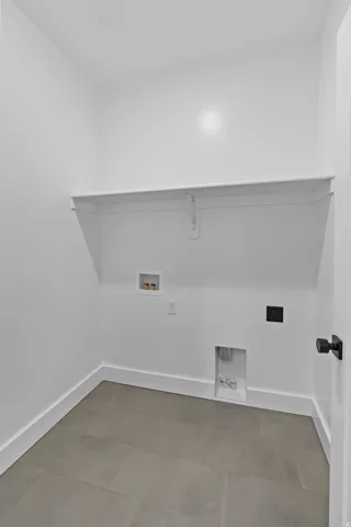 Utility area featuring an integrated shelf, tile flooring, and clean white walls
