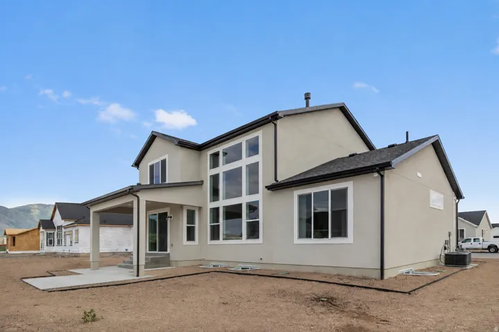 Multi-story stucco exterior with a covered patio, extensive window fenestration, and a ground-level concrete patio