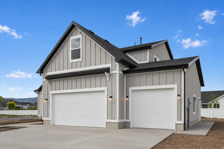 Modern farmhouse exterior featuring board and batten siding, dark shingle roofing, and a two-car garage with carriage-style doors