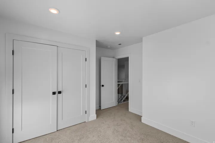 Recessed ceiling lighting, white painted trim, and neutral carpeting