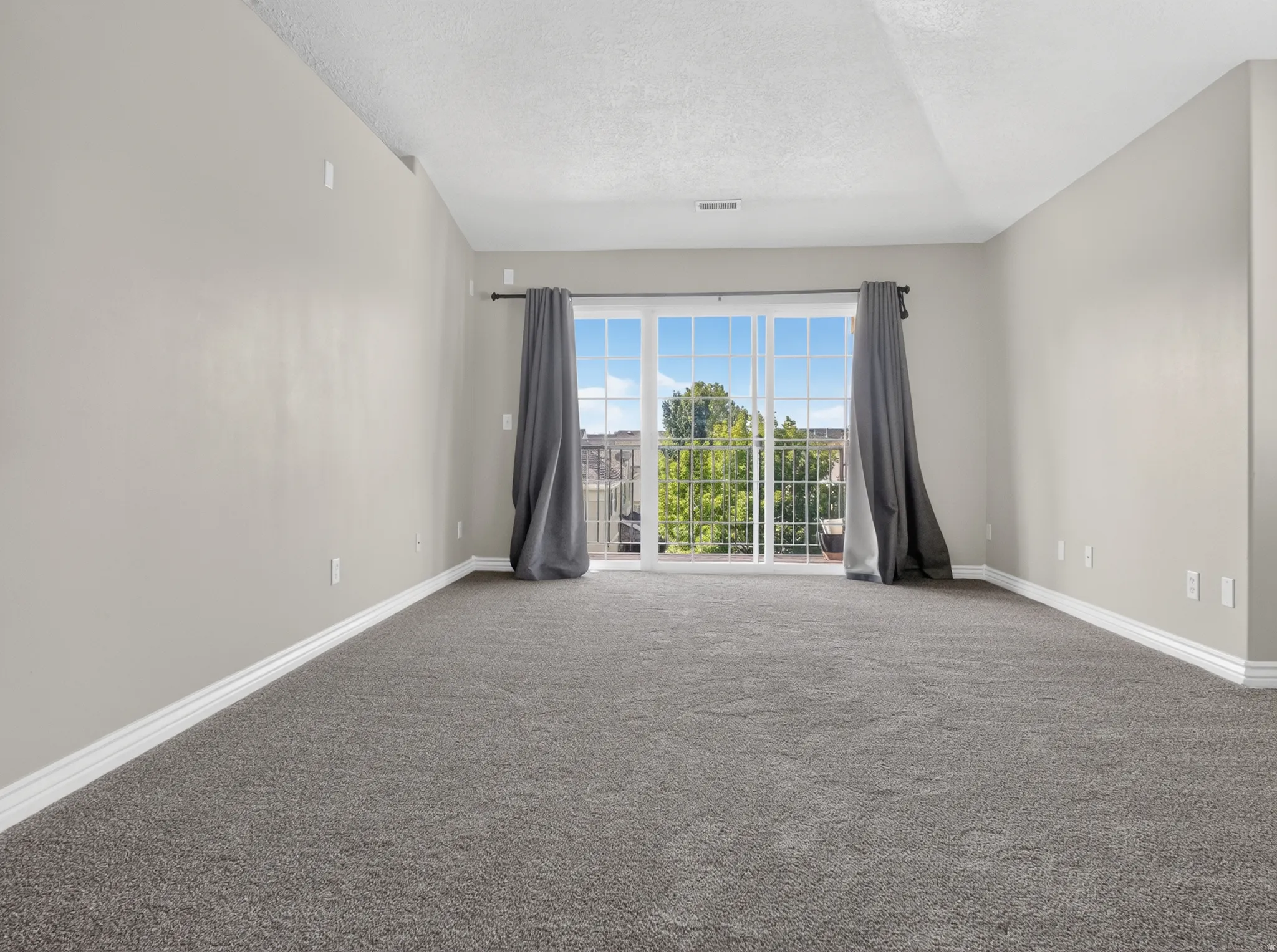 Neutral wall finishes, textured carpeting, sliding glass door, and white trim