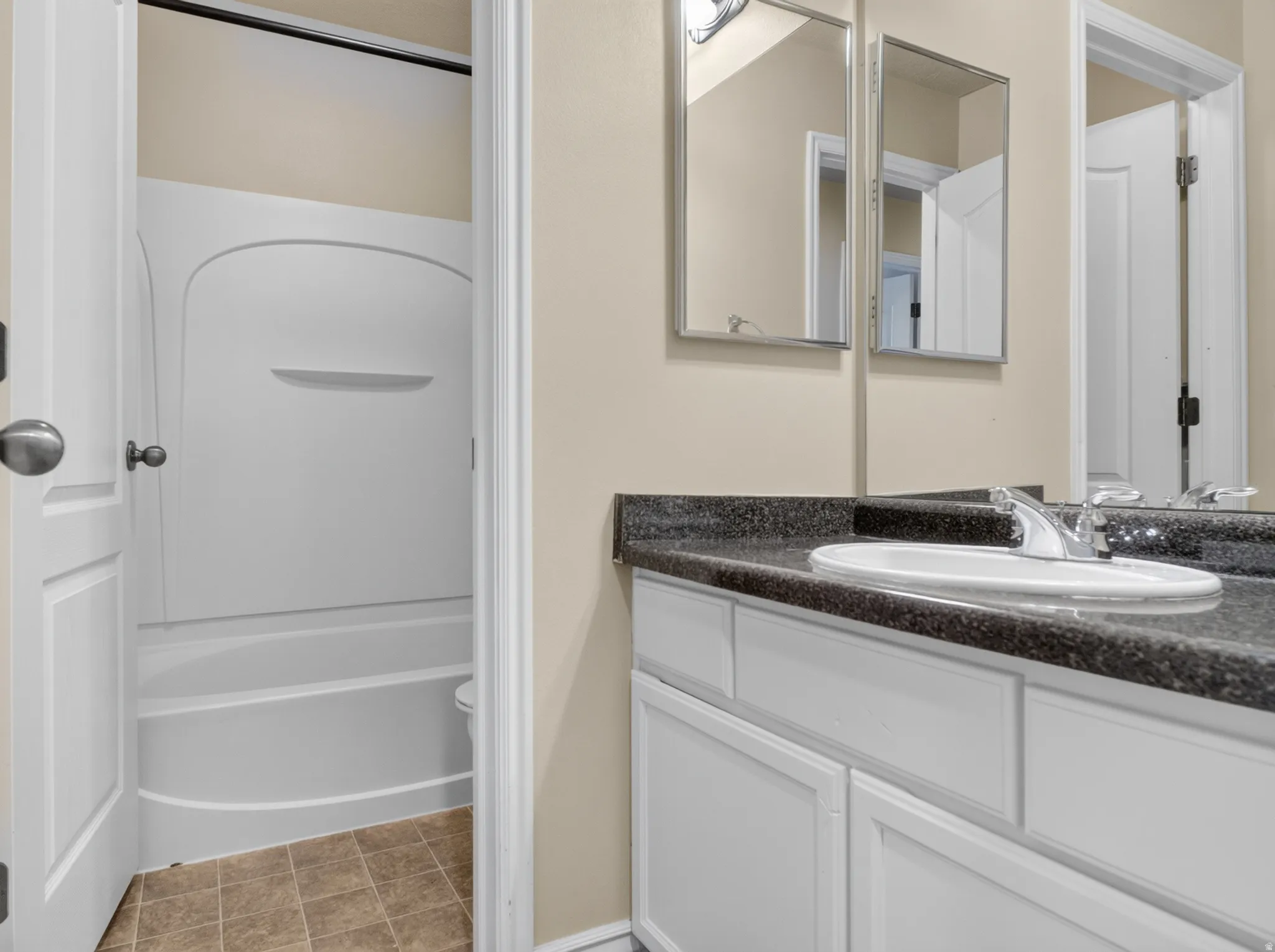 Vanity with a built-in sink, dark countertop, and white cabinetry