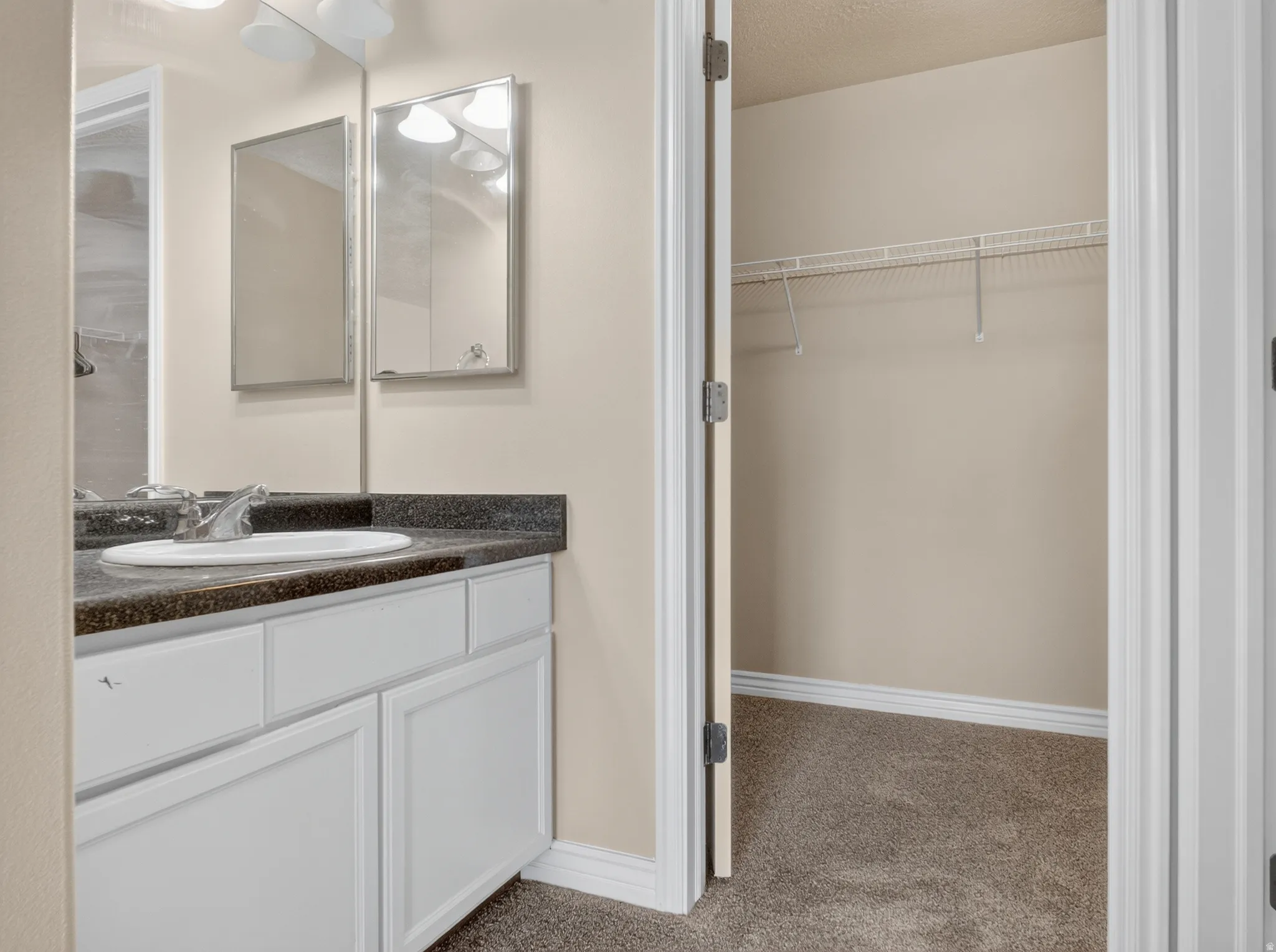 Bathroom vanity with an integrated sink, dark speckled countertop, and white cabinetry