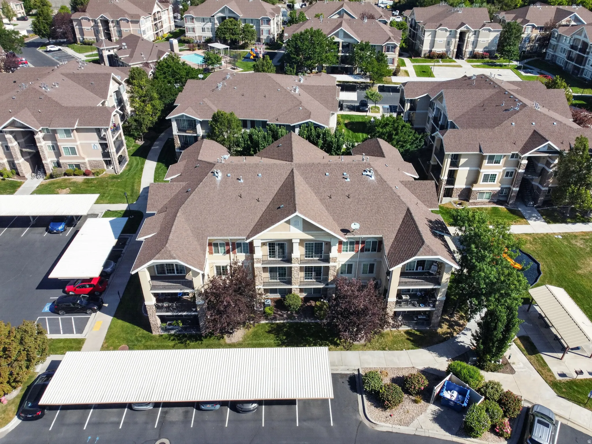 Multi-story residential buildings with balconies, covered parking structures, and landscaped green spaces