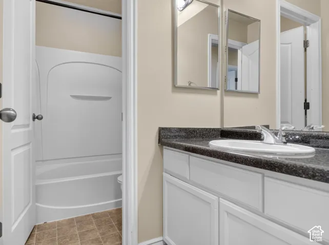 Vanity with a built-in sink, dark countertop, and white cabinetry
