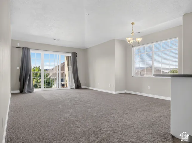 Expansive room with neutral carpeting, light-toned walls, and a large window with horizontal blinds