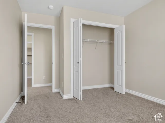 Neutral wall paint, carpeted flooring, white trim, bi-fold closet doors, and wire shelving