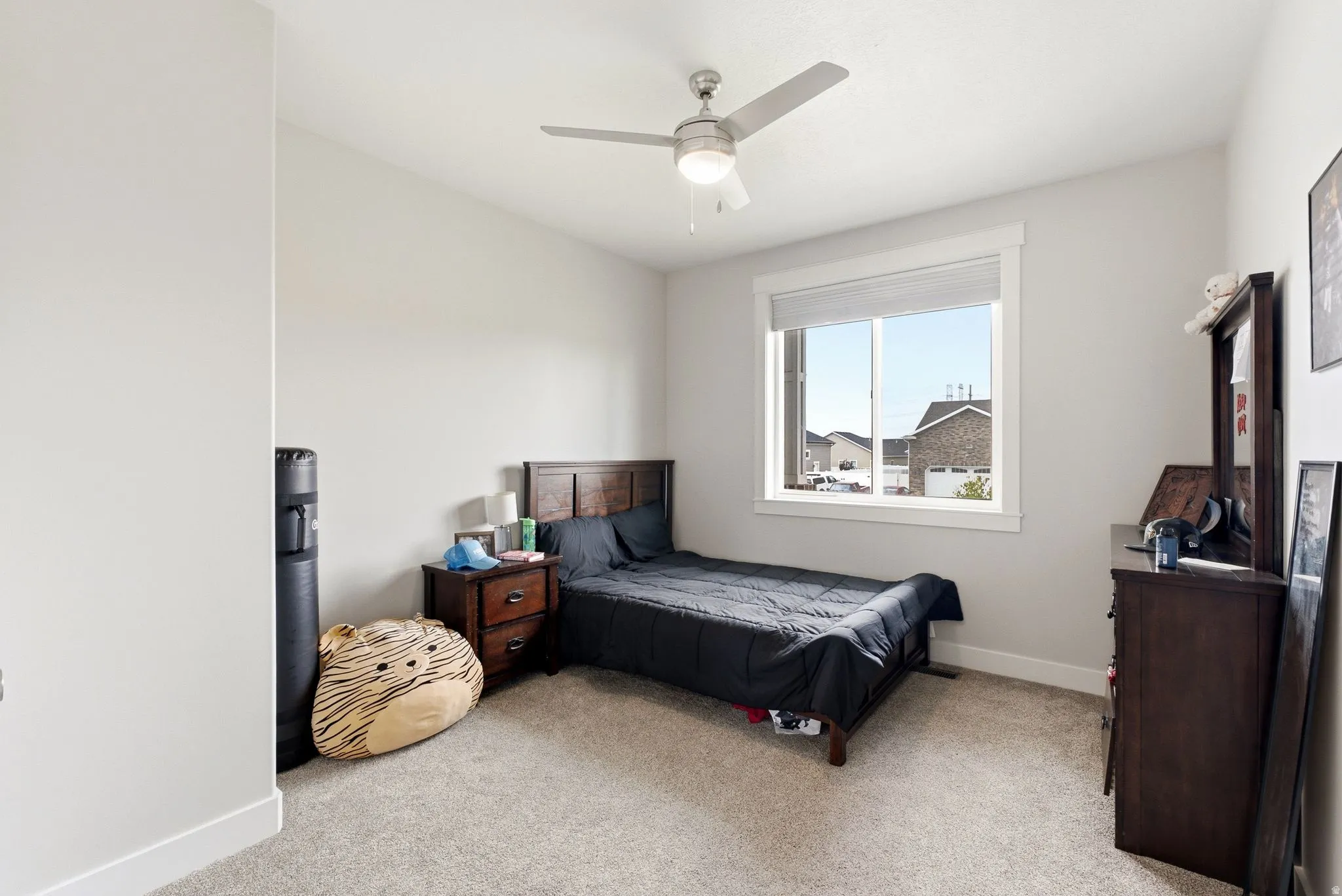 Carpeted flooring, white walls, rectangular window with white trim, ceiling fan with integrated lighting, wood-finish headboard