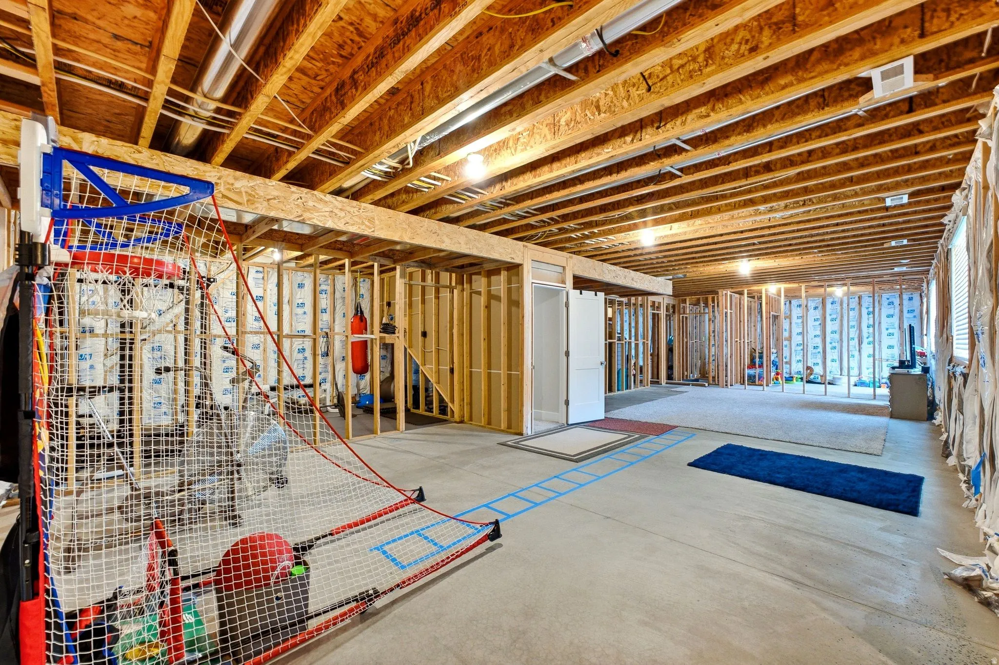 Unfinished lower level with exposed ceiling joists, concrete flooring, framed interior walls, and recessed lighting