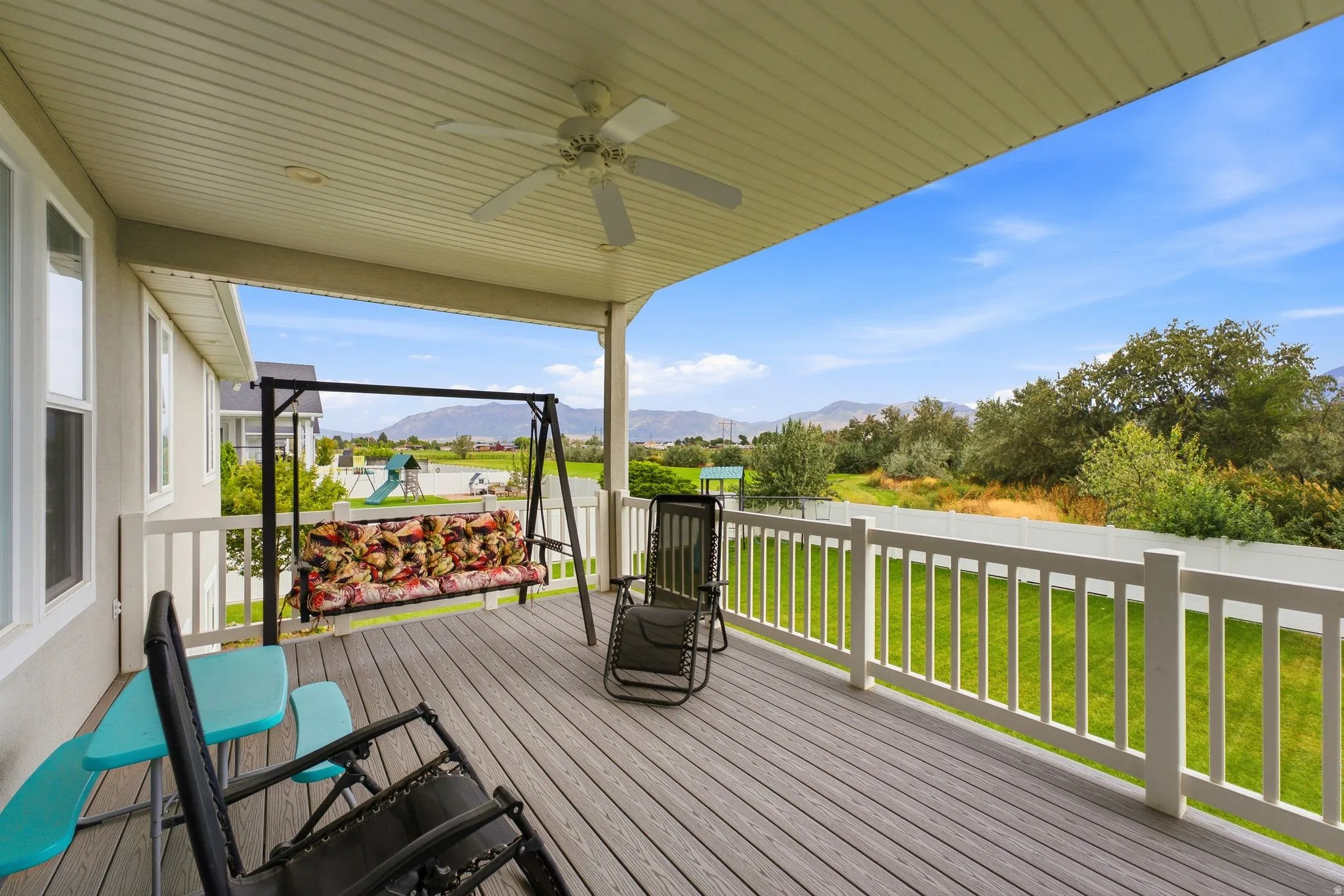 Covered outdoor deck with a ceiling fan, composite decking, and white railing