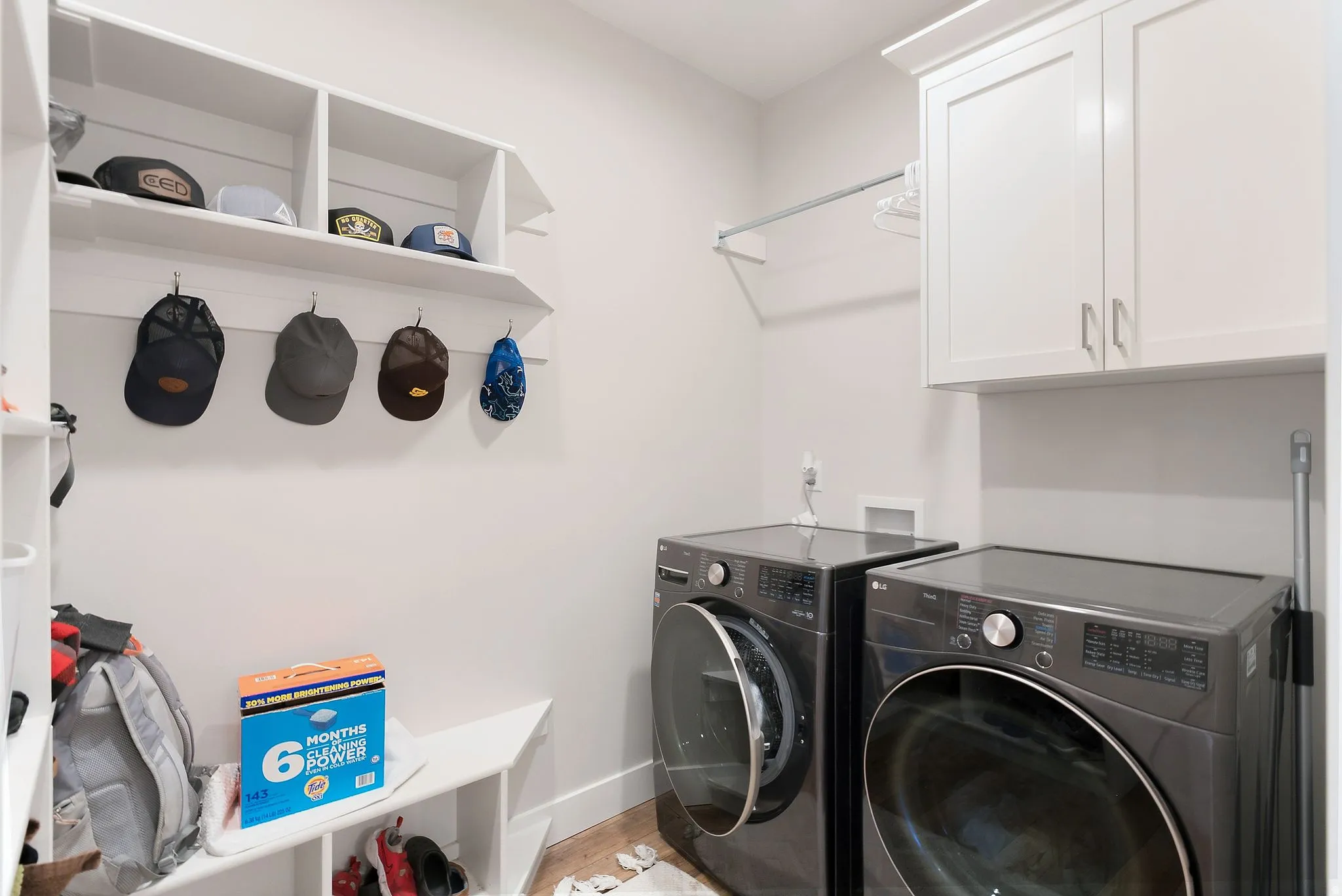 Utility room featuring built-in cabinetry, a hanging rod, and wood-finish flooring