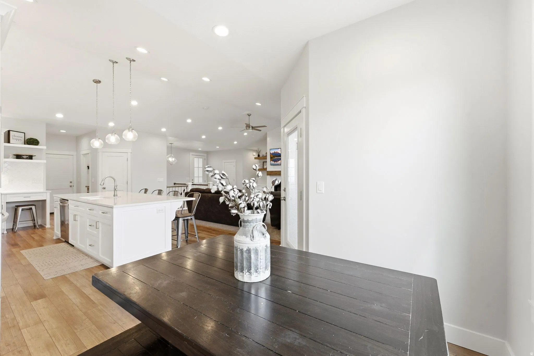 White kitchen island with a built-in sink, pendant lighting, recessed lighting, and wood-finish flooring