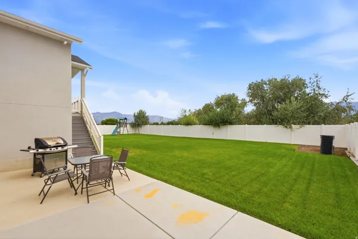 Expansive backyard featuring a manicured lawn, a full privacy fence, and a concrete patio