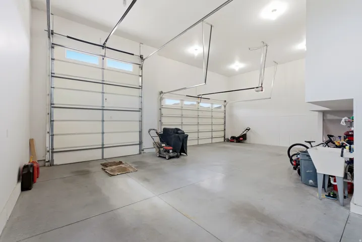 Two overhead garage doors with frosted window panels, concrete flooring, and recessed ceiling lighting