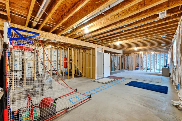 Unfinished lower level with exposed ceiling joists, concrete flooring, framed interior walls, and recessed lighting