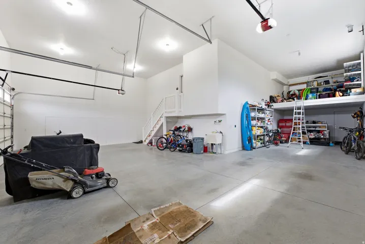 Spacious garage featuring a concrete floor, high ceilings, a utility sink, and overhead storage