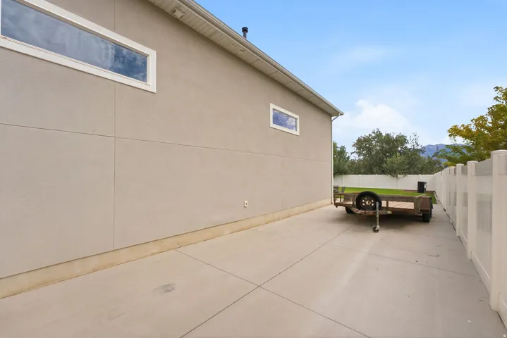 Concrete side yard with a white vinyl fence and a stucco exterior