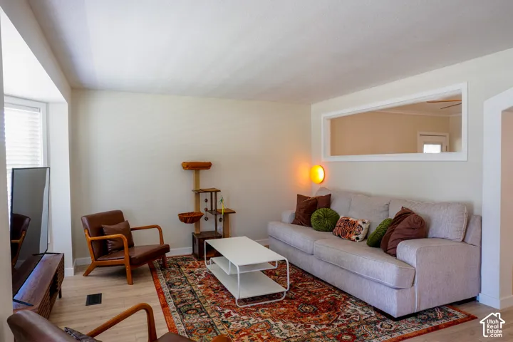 Bright, open living room featuring hardwood flooring, recessed ceiling details, and abundant natural light from multiple windows