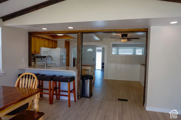 Kitchen featuring wood-finish cabinetry, white appliances, and a breakfast bar with a solid surface countertop