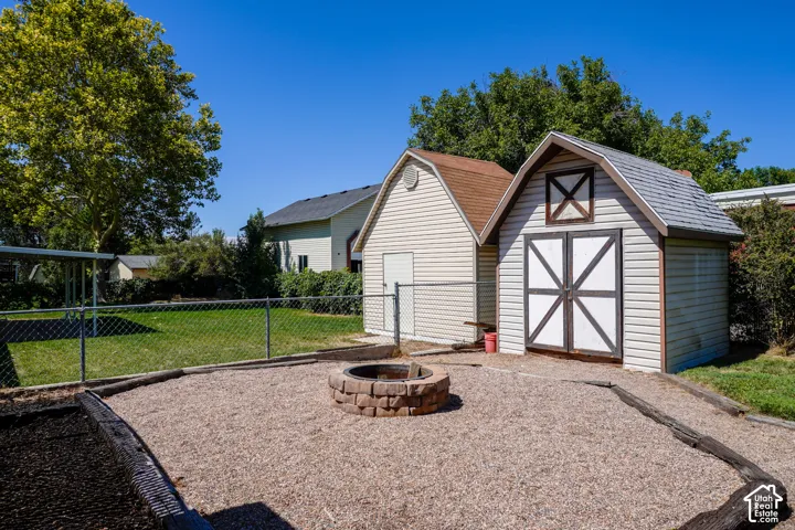 Gravel patio with a stone fire pit, bordered by railroad ties