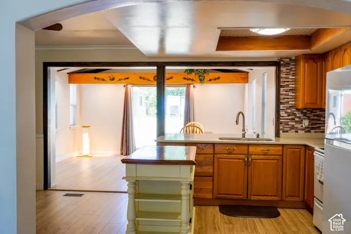 Kitchen featuring wood-finish cabinetry, solid surface countertops, and a mosaic tile backsplash