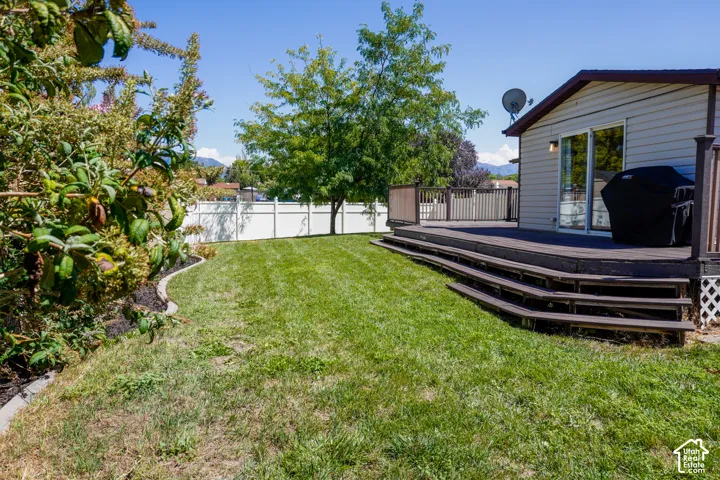 Expansive lawn with a tiered wood-finish deck and white privacy fencing