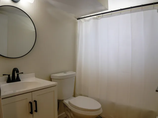 White vanity with dark cabinet pulls, undermount sink, and matte black faucet