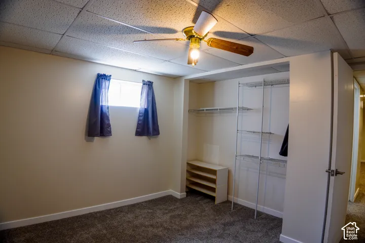 Recessed window, ceiling fan with light fixture, carpeted flooring, built-in closet shelving, and a neutral wall color