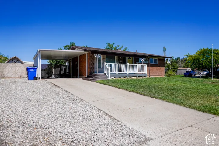 Brick and siding exterior, expansive front lawn, covered carport, concrete driveway, and front porch with white railing