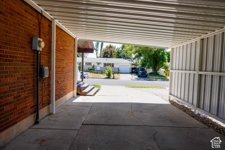 Covered carport with corrugated metal roof and brick facade, offering protected parking and outdoor storage space