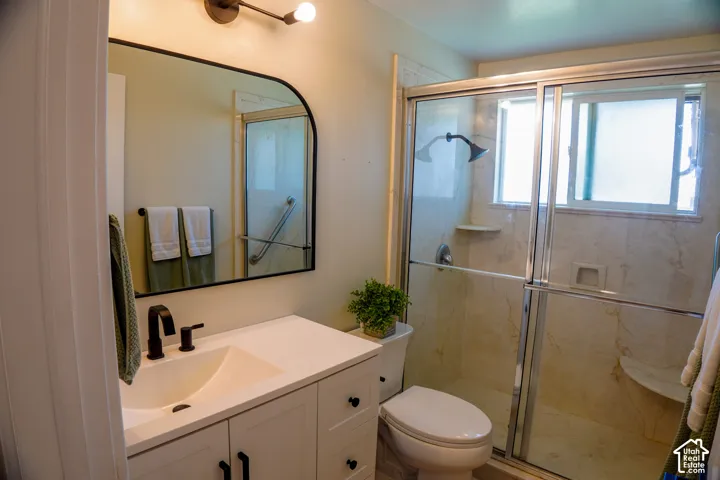 White vanity with black hardware and an integrated sink, framed mirror, and a shower enclosure with sliding glass doors