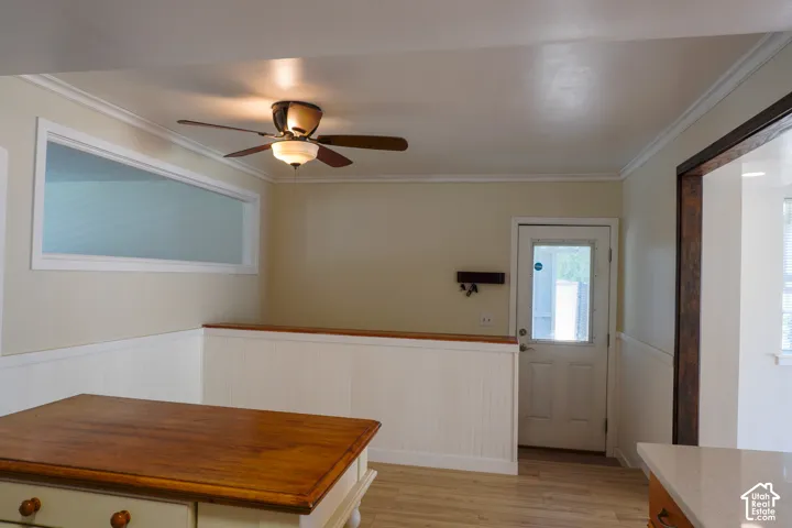 Wood-finish flooring with wainscoting details, ceiling fan with integrated lighting, and a transom window