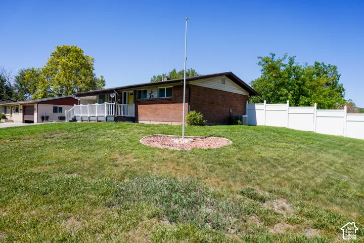 Brick siding exterior with a white deck, carport, and a white privacy fence