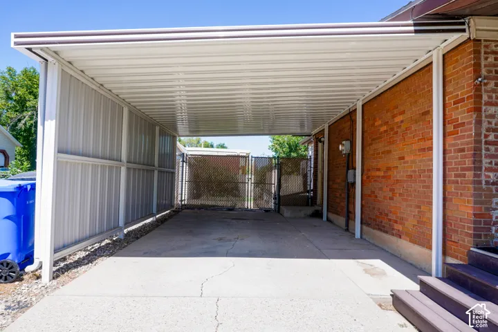 Covered carport with corrugated metal roof and open-sided design, providing sheltered parking and storage space