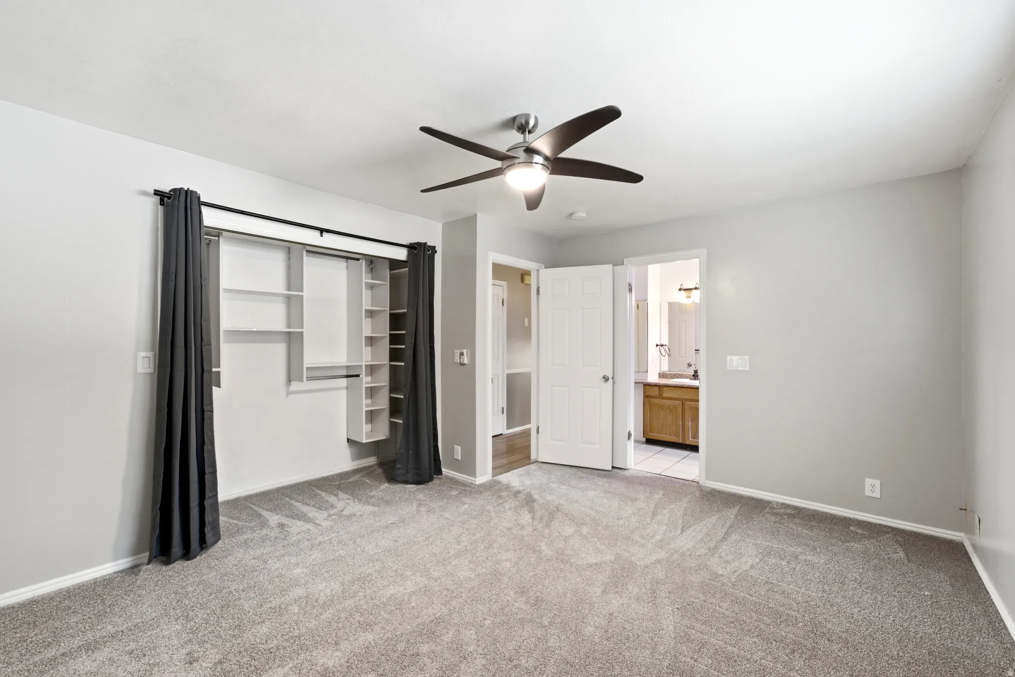 Plush carpet flooring, ceiling fan with integrated lighting, built-in closet shelving, and a bright interior paint palette